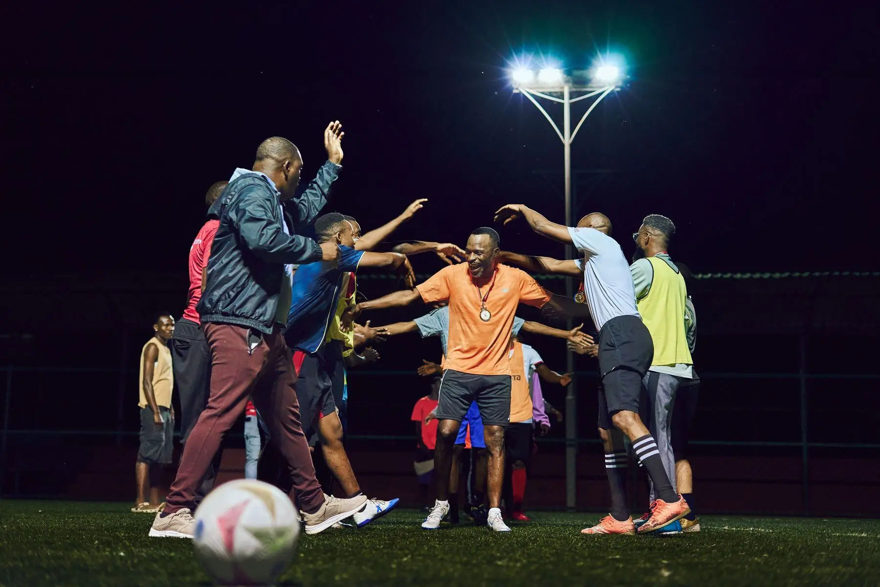 Friends playing football under floodlights